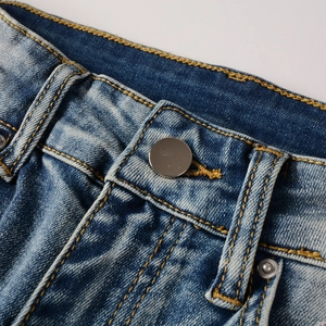 Detailaufnahme des Herrenjeansbundes mit Kontrastnähten und poliertem Metallknopf