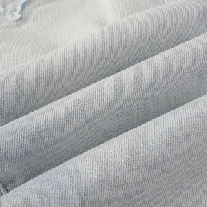 Detail von hellblauem Jeansstoff mit Distressed-Rissen und Köperbindung-Struktur