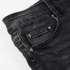 Détail de jean slim pour homme montrant la poche avec rivets en métal et texture délavée