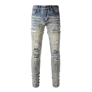 Close-up of distressed blue denim with striped knee patches and colorful paint drips