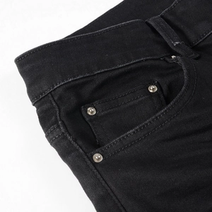 Close-up of black denim jeans detailing stitching, metal rivets, and fabric texture