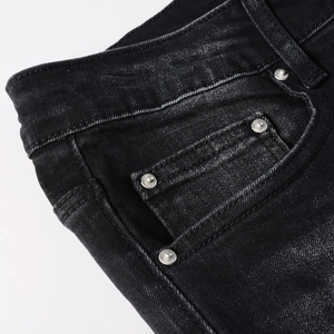 Detailed macro of washed black denim fabric with metal rivets and double stitching