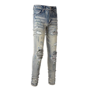 Detail of light blue distressed jeans with paint splatters and leather patches
