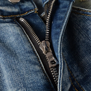 Nahaufnahme von silbernem Metallreißverschluss und gelben Nähten auf blauer Denim-Jeans