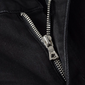 Macro detail of high-quality silver metal zipper on black embroidery ripped jeans