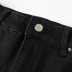 Macro detail of black slim jeans waistband featuring silver metal button and denim texture