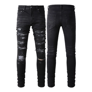 Detailed view of black slim-fit distressed denim jeans with ribbed motor-style patches