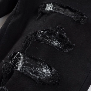 Distressed black denim jeans featuring detailed cobra skin texture embroidery inside the rips