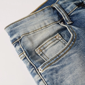 Detailansicht der Jeans-Taschen mit Silbernieten und gewaschener blauer Stofftextur