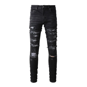 Detail of black distressed skinny jeans for men featuring white striped patches under rips