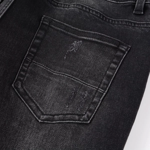Gros plan d'une poche en jean noir délavé avec détails déchirés et texture usée vintage