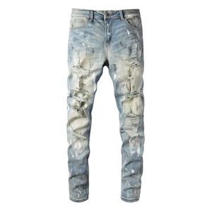 Slim fit light blue distressed jeans for men with vintage paint splatters and ripped holes