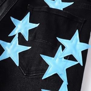 Dettaglio di stelle in pelle blu cucite con filo bianco sulla tasca posteriore del jeans