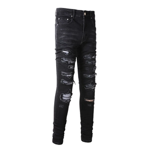 Macro detail of charcoal black ripped jeans featuring washed texture and distressed knee holes