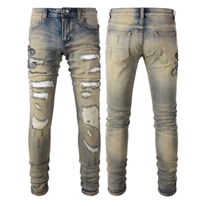 Détail de la broderie serpent et texture déchirée sur ce jean slim bleu délavé