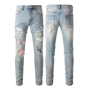 Detail view of men's slim blue jeans showing ripped holes with colorful striped fabric lining