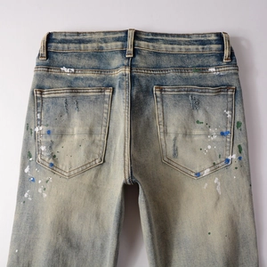 Detail of splash ink paint design and distressed wash on men's slim fit denim jeans