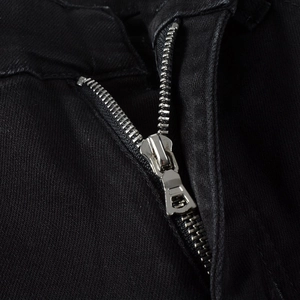 Detail of silver metal zipper and precise stitching on black slim stretch denim jeans