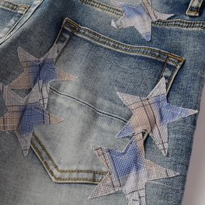Detail von sternförmigen Aufnähern mit Fransen an der Gesäßtasche dieser blauen Jeans