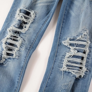 Detailed macro view of heavy distressed denim with blue frayed holes and fibers