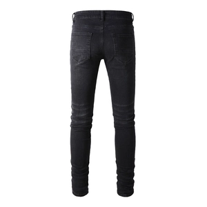 Macro detail of men's black slim fit jeans back pockets and denim texture on white background