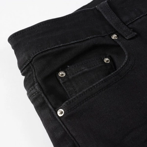 Macro shot of black denim jeans showing fabric texture and silver metal rivet reinforcement