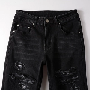 Detailed view of distressed black jeans with ripped denim texture and metal button