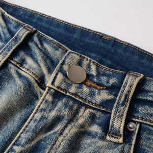 Detail of blue denim jeans waist with metal button and classic orange contrast stitching