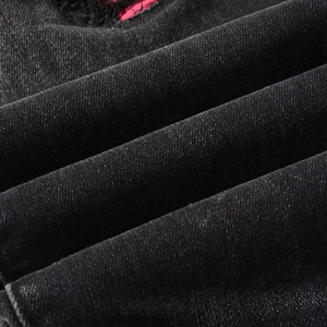 Détail macro d'un jean slim noir avec des déchirures et une doublure en tissu rouge