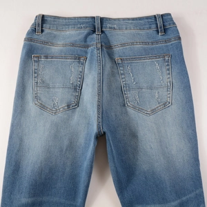 Detail of distressed back pocket and faded denim texture on blue men's shorts
