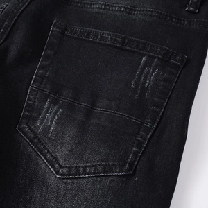 Close-up of washed black denim jeans back pocket with distressed detail and stitching