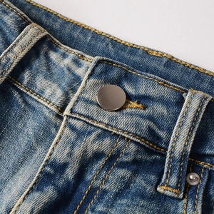 Détail macro de la taille en denim bleu foncé avec bouton argenté et surpiqûres jaunes