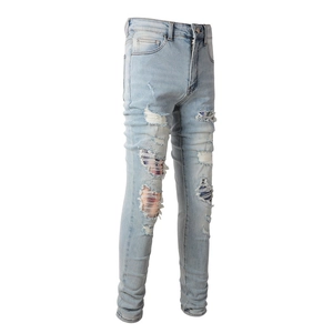 Close-up of slim fit light blue ripped jeans featuring colorful tie-dye distressed patches