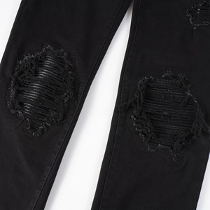 Detail of high street black ripped jeans featuring distressed knee fibers and denim texture
