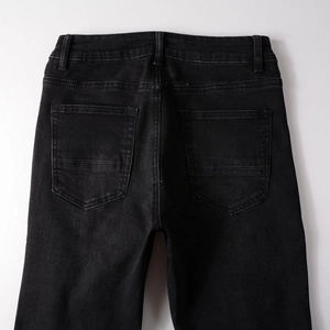 Detail of high waist black denim pants featuring square back pockets and neat stitching