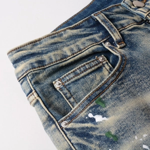 Close-up of vintage wash denim jeans with paint splatters and metal rivet details