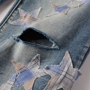 Detailaufnahme von Distressed-Jeans mit blau-weiß karierten Stern-Patch-Details