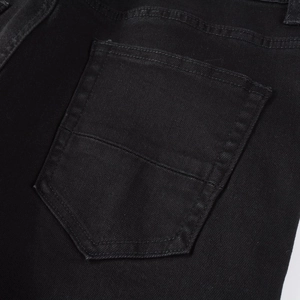 Detailed close-up of back pocket stitching and twill denim texture on black jeans