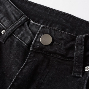 Macro shot of black washed denim waist detailing with silver button and double stitching