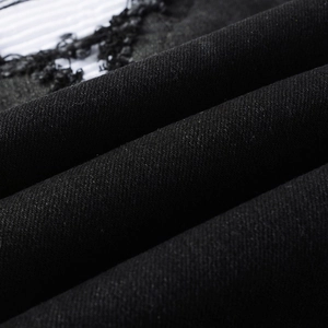 Detail of black denim jeans featuring distressed ripped holes and black lace patchwork detail