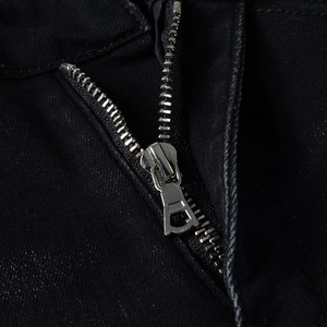 Dettaglio della cerniera in metallo argentato su jeans neri elasticizzati slim fit