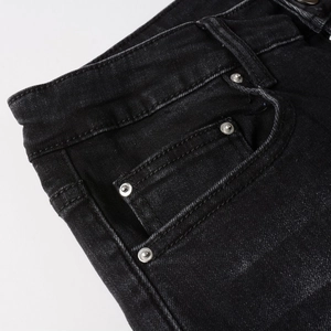 Detail view of black denim jeans waist with belt loops and silver metallic rivets