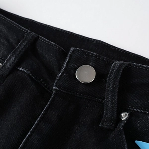 Vista macro del bottone d'argento e cuciture di alta qualità sui jeans neri lavati