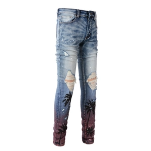 Detail of ripped jeans with palm tree print, white paint splashes and red gradient hem