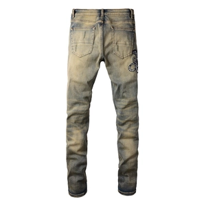 Détail du jean denim délavé au sable avec broderie serpent et style vintage