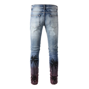 Detail of slim fit jeans with palm tree silhouettes, paint drips and gradient wash