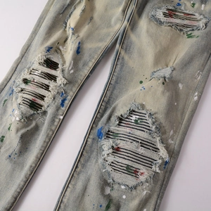 Distressed slim fit jeans for men featuring paint splatter and striped knee patches