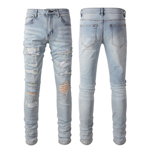 Detail of light blue distressed jeans featuring ripped holes and a slim fit cut