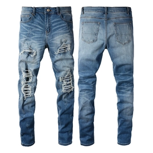 Detail of light blue distressed jeans showing washed cat whiskers and heavy repair patches