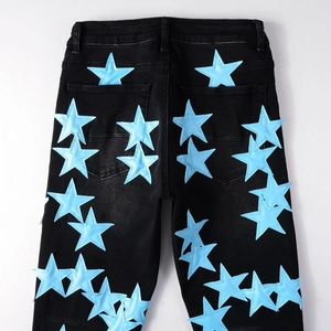 Dettaglio jeans in denim nero con toppe in pelle a stella blu chiaro cucite sul retro